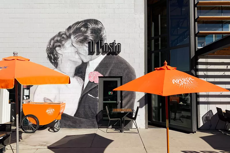 Image: orange umbrellas in front of a mural of two people kissing