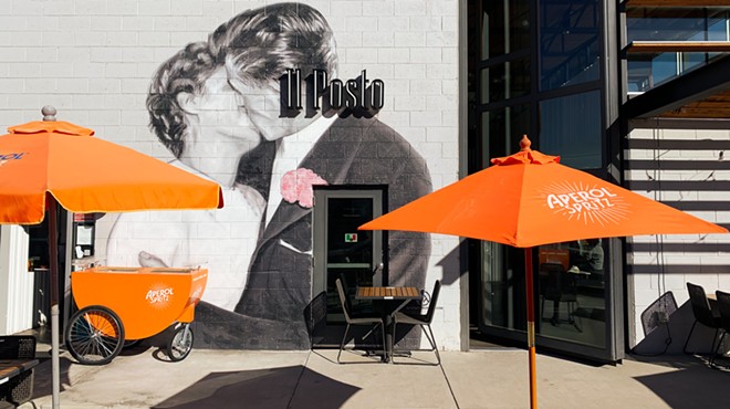 orange umbrellas in front of a mural of two people kissing