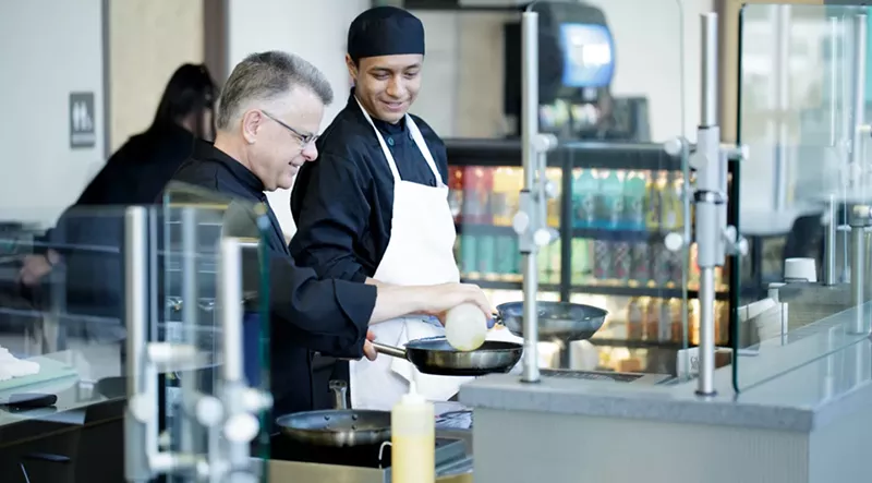 Image: Chef Tim Inzano (left), and an Emily Griffith culinary arts student work the omelet station during breakfast at Emily's Cafe.
