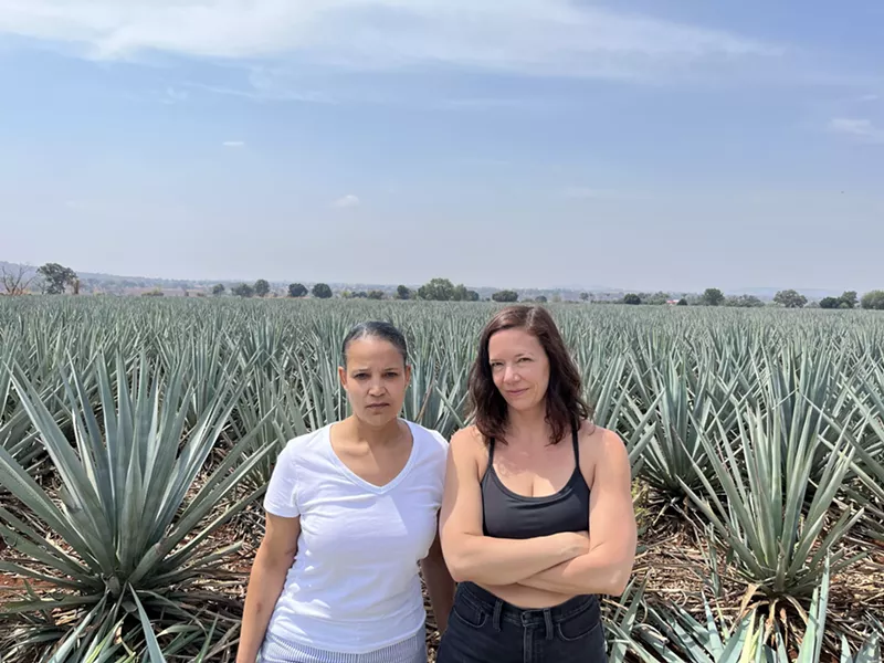 Image: Two women standing in front of a field of agave plants.