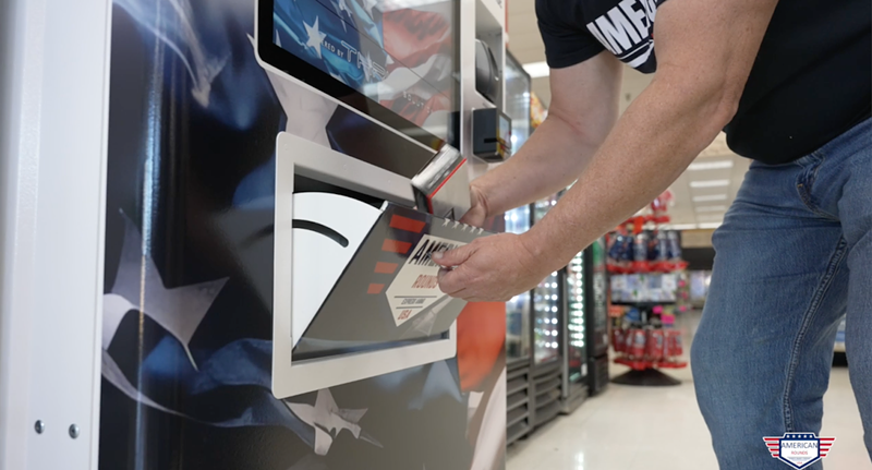 Image: A man takes ammo from a vending machine.