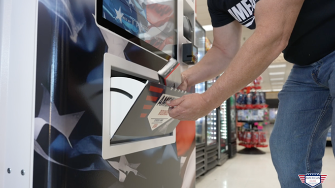A man takes ammo from a vending machine.