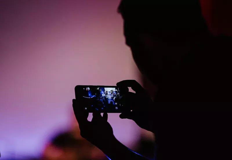 Image: Person records video on phone in shadows