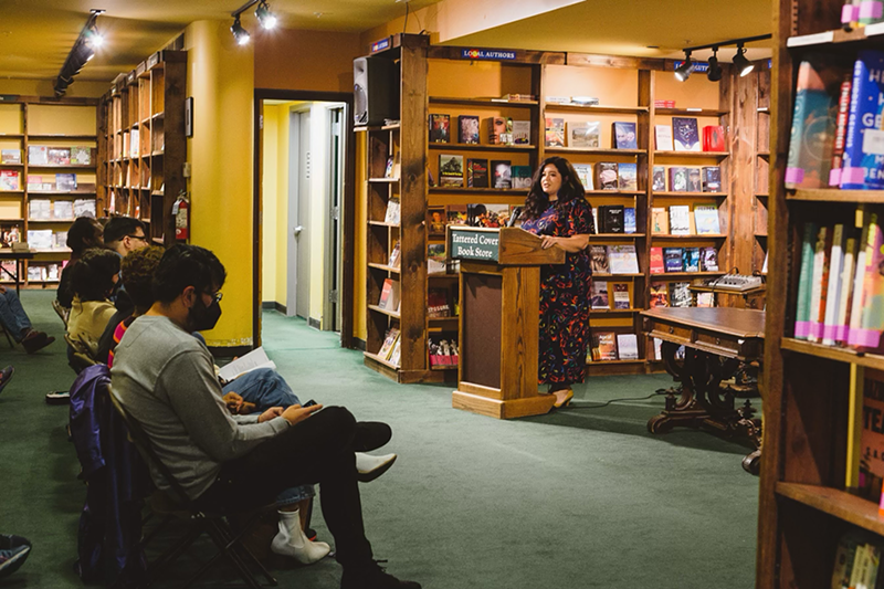 Image: woman reading at a podium in a bookstore