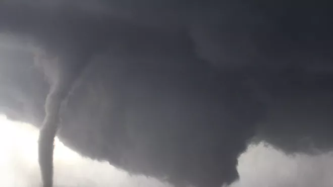 Red pickup truck in front of tornado on road