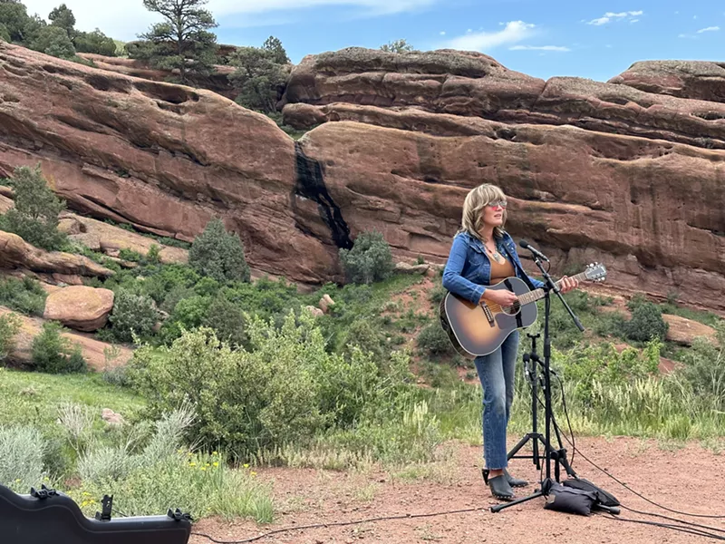 Image: Musician with guitar playing in front of rock face.