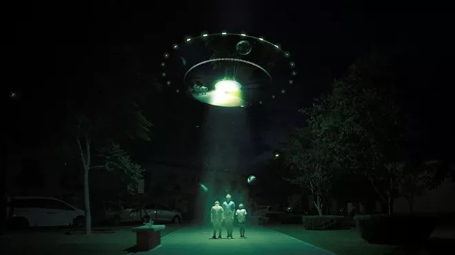 Aliens stand under a green light