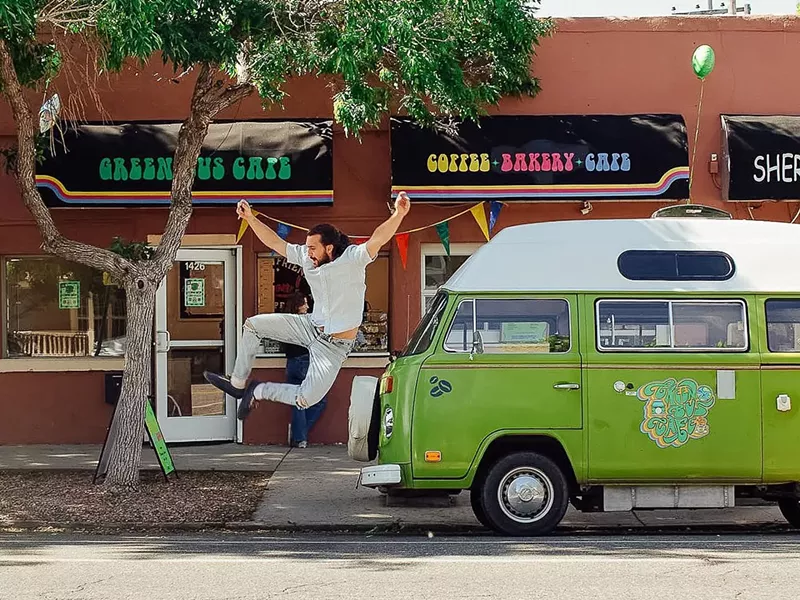 Image: a man jumping in the air next to a vintage green bus