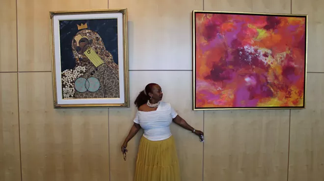 Black woman stands in front of two paintings.