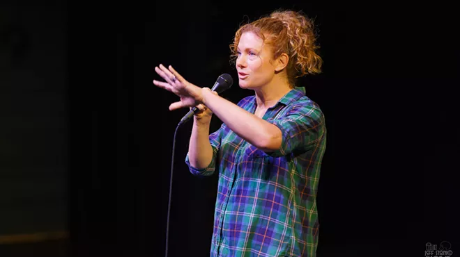 A comedian speaks into a microphone onstage.