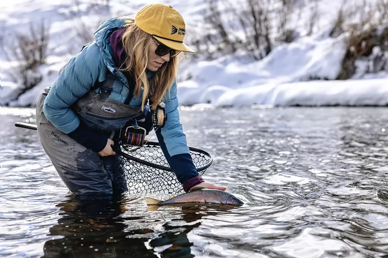 Image: A female fly fishing guide releasing a trout into a river