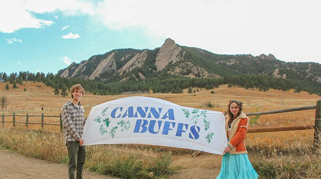 College students hold a CannaBuffs banner in front of Colorado mountains