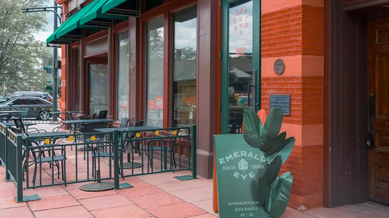Image: a green sign in front of the entryway of a brick building