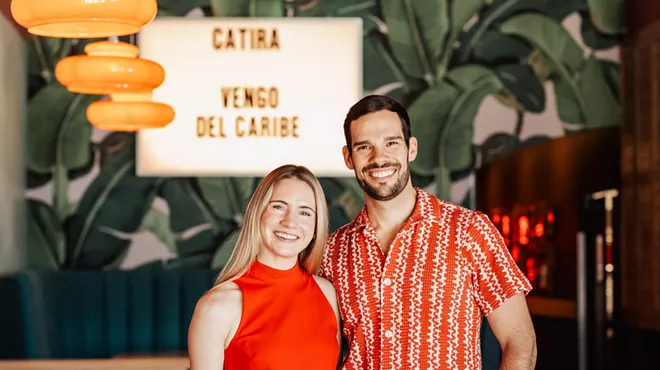 man and woman in front of restaurant sign