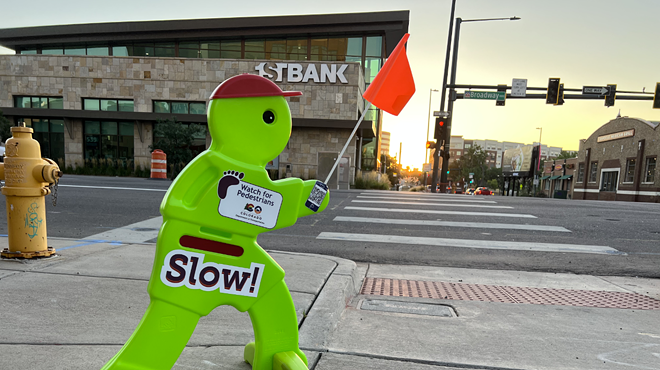 A green plastic boy with a red hat and a sign that says "slow" on his stomach.