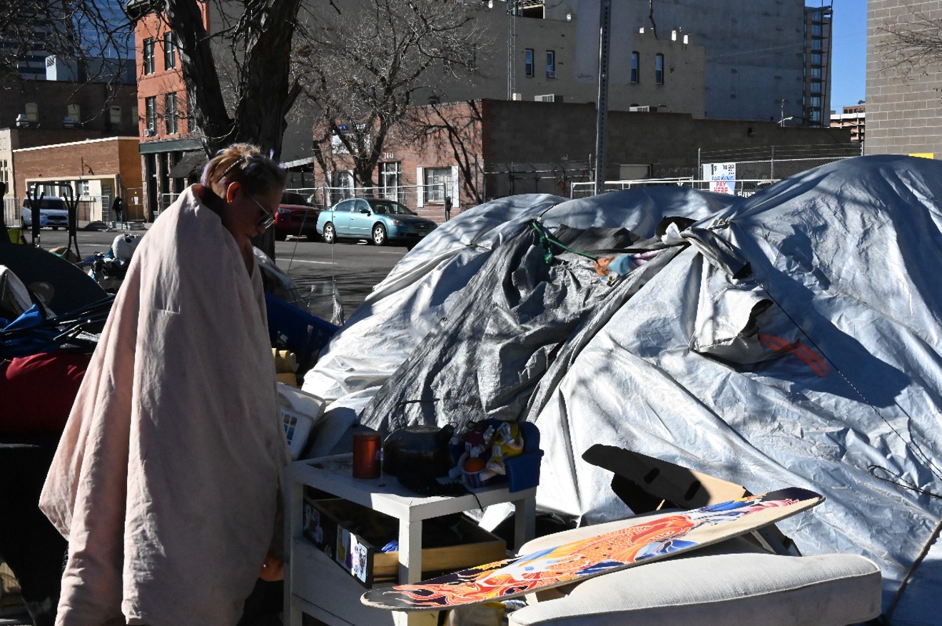 A homeless resident stands outside her tent at the corner of 21st and Curtis streets.