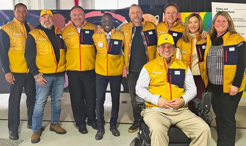 Image: A group of people wearing yellow vests pose for the camera.