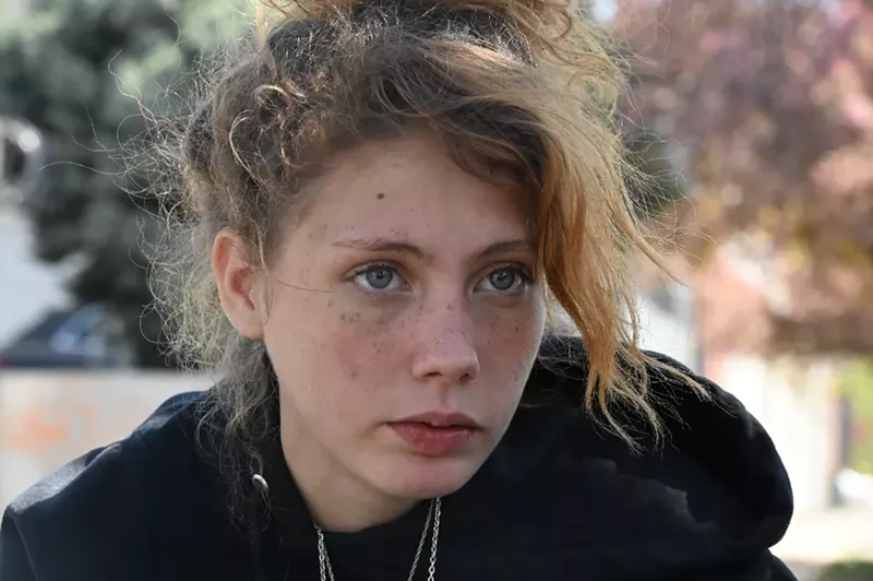 Image: A young homeless woman watches a sweep.