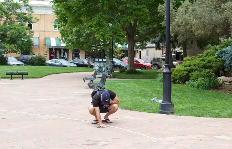 Image: Man kneels down on sidewalk
