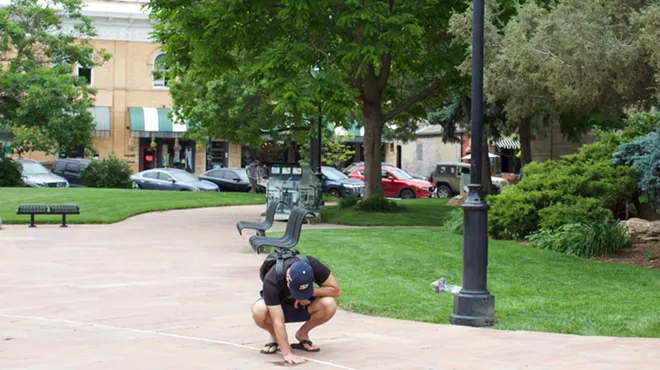 Man kneels down on sidewalk