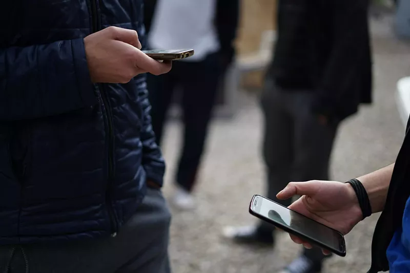 Image: Two people holding cell phones, scrolling on social media.
