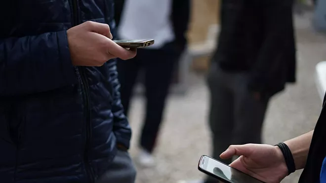 Two people holding cell phones, scrolling on social media.