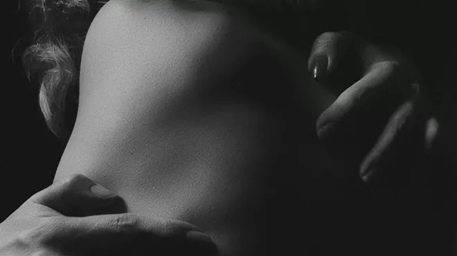 A black and white photo of hands hugging a body