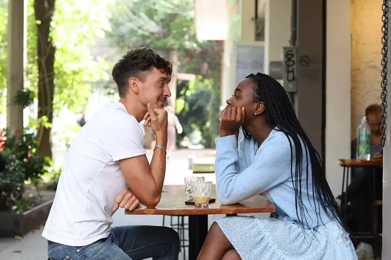 Image: white man and black woman at table.