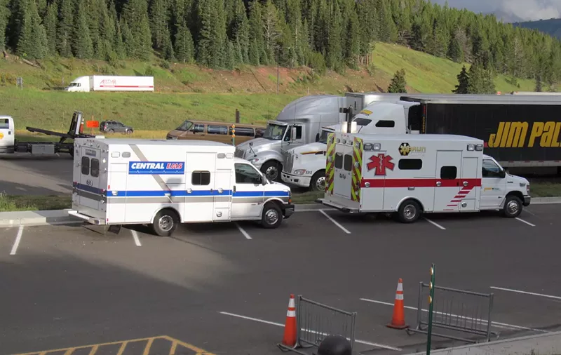 Image: two ambulances parked in front of trees in the Colorado mountains