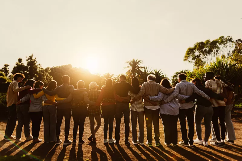 Image: group of people hugging at sunrise