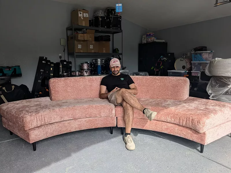 Image: Pedro Urbina, the founder and host of Pink Sofa Hour, takes a seat on stage.