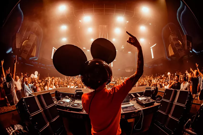 Image: man with mouse mask on his head deejays to an audience