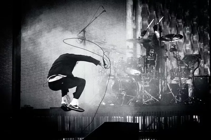 Image: member of Deftones jumping on stage with a microphone