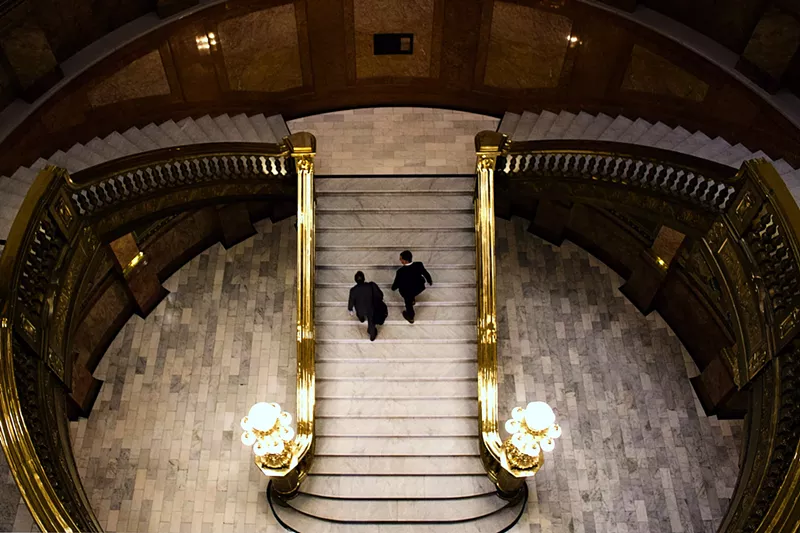 Image: Two men in suits walk up the stairs of the Colorado Capitol building.