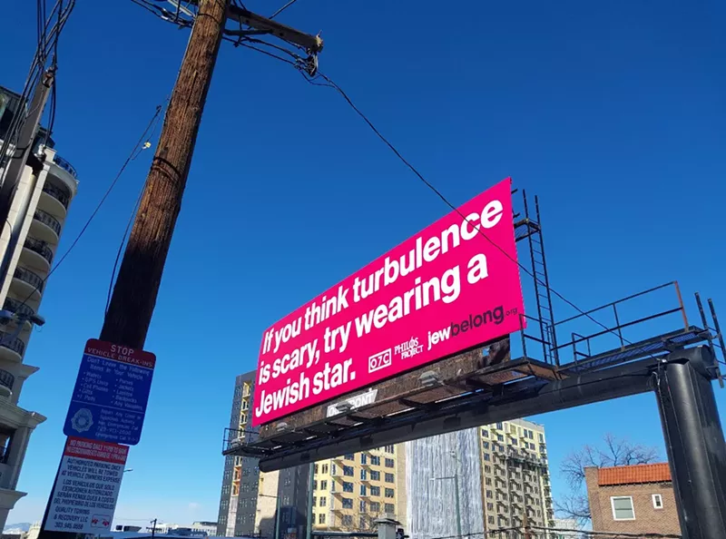 Image: A pink billboard reads, “If you think turbulence is scary, try wearing a Jewish star.”