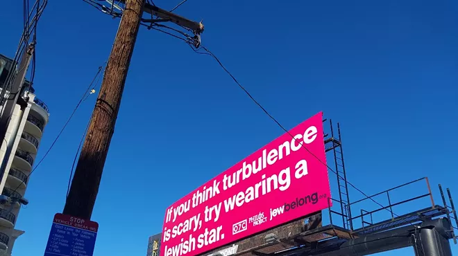 A pink billboard reads, “If you think turbulence is scary, try wearing a Jewish star.”