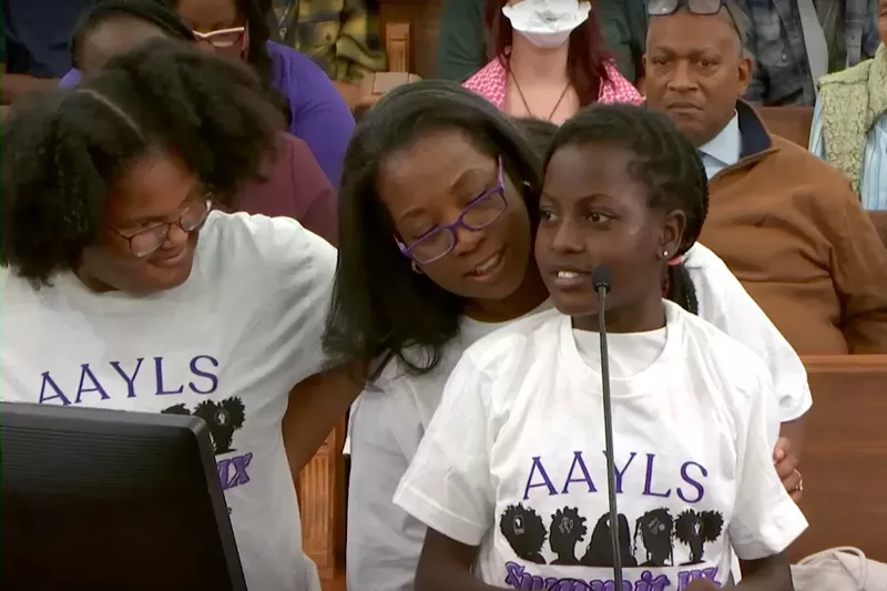 Image: Dr. Plashan McCune (center) with two young members of the African American Young Ladies Summit program during a city council presentation.
