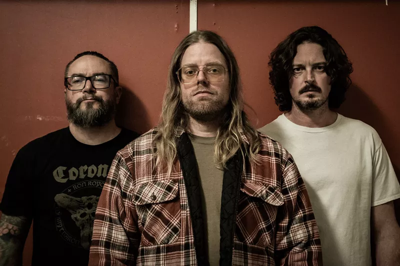 Image: three metal bandmembers pose for a photo.
