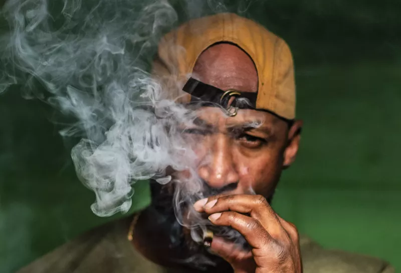Image: Man with backwards hat smokes joint