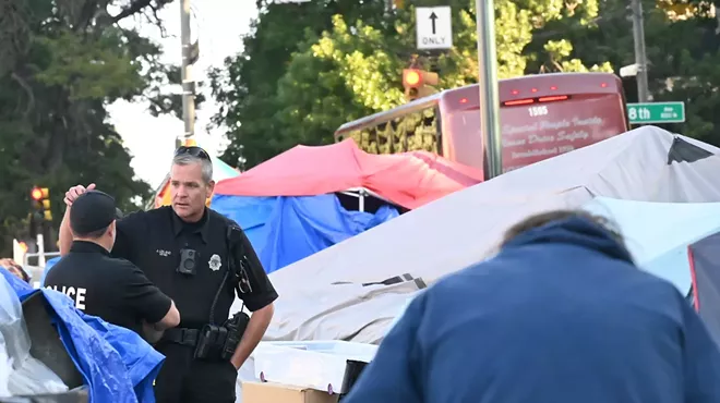 Denver Police officers talk at the corner of 8th Avenue and Logan Street.