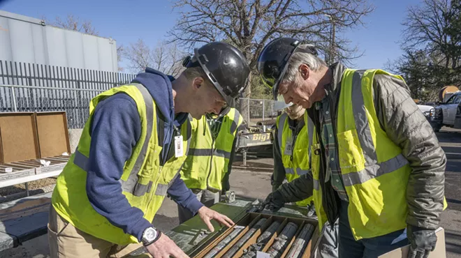 People in yellow vests examine specimen