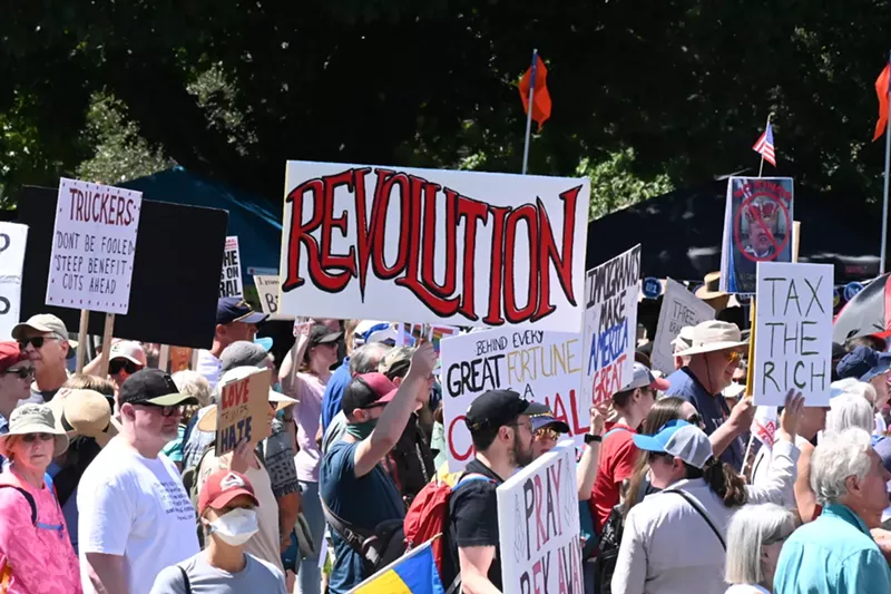 Image: Protesters march and hold signs, one reading "revolution."