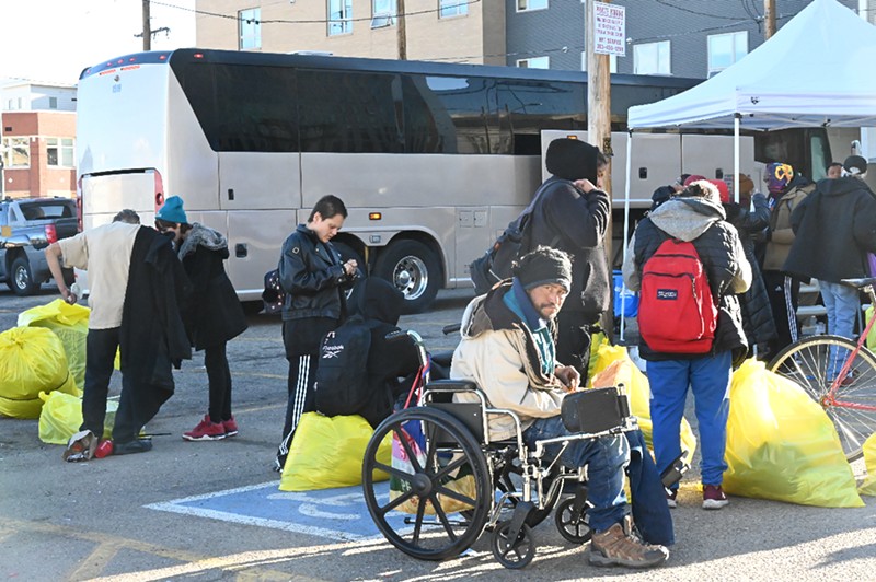 Homeless residents at an encampment in the Ballpark District prepare to board a bus that will take them to transitional housing on a December morning.