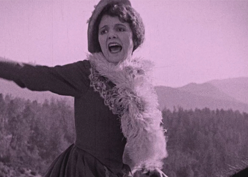 Image: woman throws out her arms yelling with a cat hanging from her neck