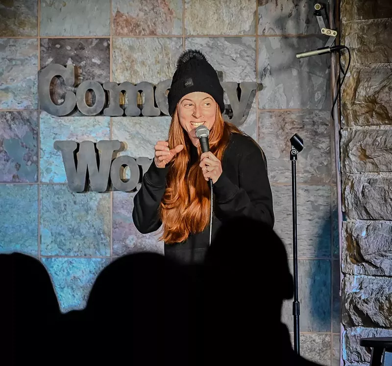 Image: red haired woman in beanie at a microphone
