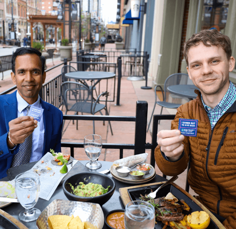 Image: two men at outdoor restaurant.