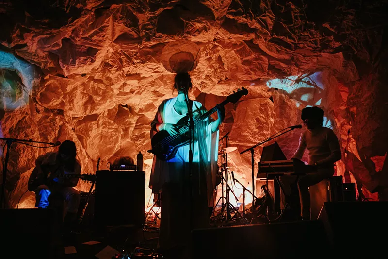 Image: A band performs against an orange background.