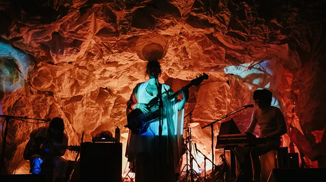 A band performs against an orange background.