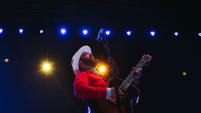 man in white hat and red shirt playing the guitar