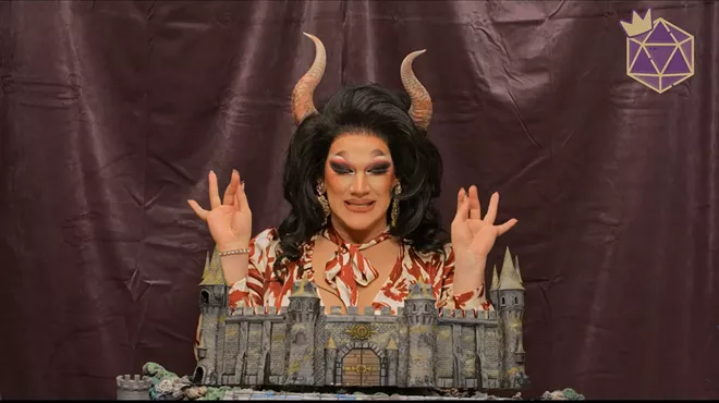 A drag queen with her hands raised